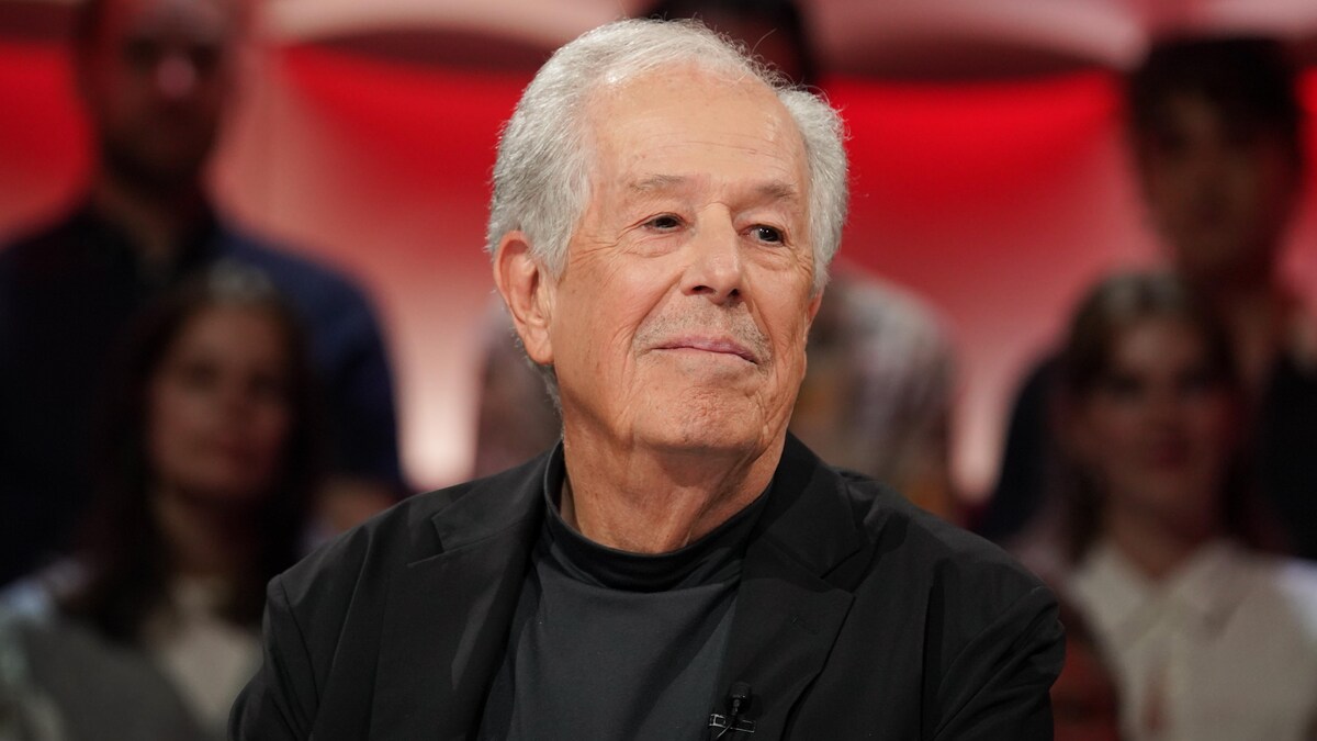Il est assis en studio.