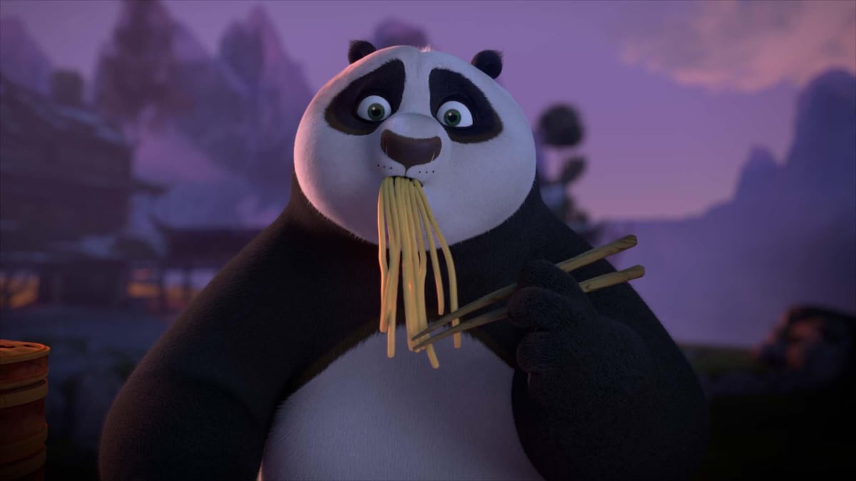 Un panda entrain de manger des nouilles avec des baguettes.