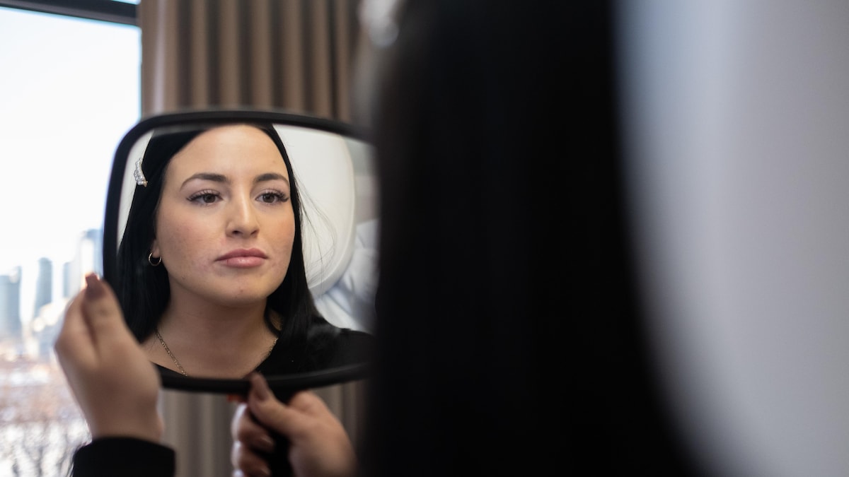 Une jeune dame se regarde dans le miroir après s'être fait injecter les lèvres.