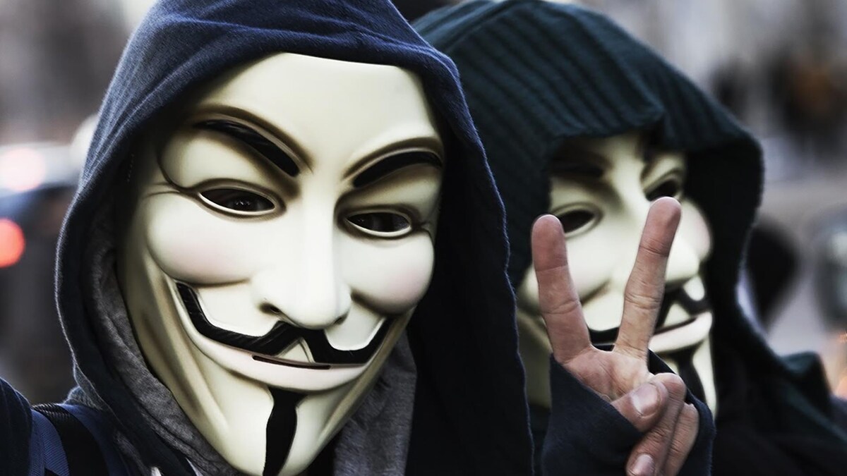 2 Hacktivists Anonymous dont l'un qui fait un signe paix