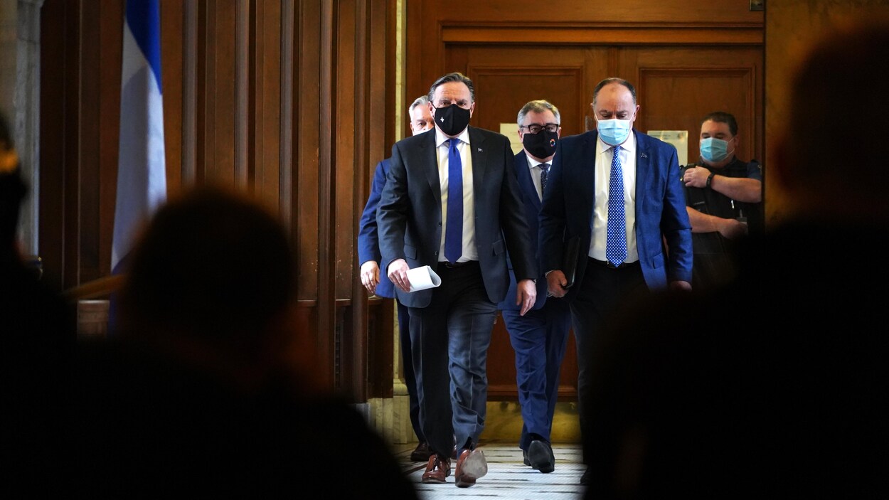 MM. Legault, Dubé et Arruda marchant dans un corridor de l'Assemblée nationale.