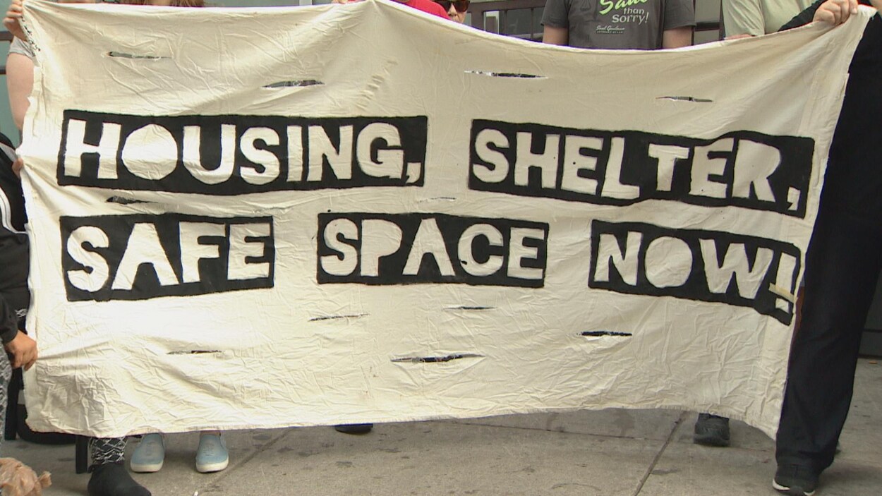 banderole des manifestants pour les sans-abri à Toronto avec écrit dessus :« Des logements, des refuges et des espaces sécuritaires, maintenant! »,
