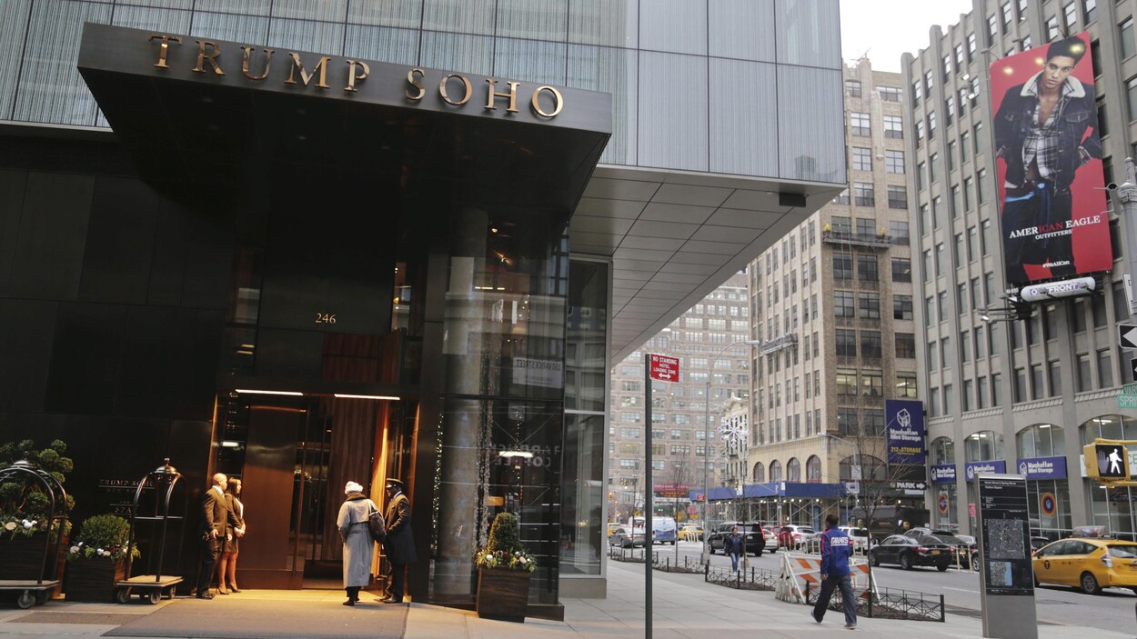 Façade en verre de l'hôtel Trump SoHo à New York, où l'on voit des clients entrer.