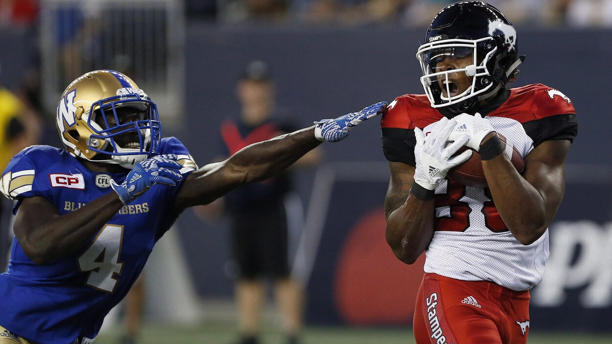 Le receveur des Stampeders, Kamar Jorden, se défait d'un plaqué de Roc Carmichael, des Blue Bombers, pour inscrire un touché.