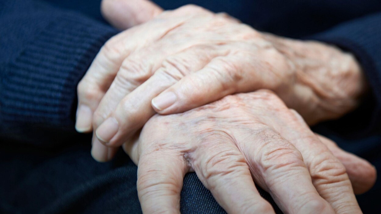 Gros plan sur les mains croisées d'une personne âgée.