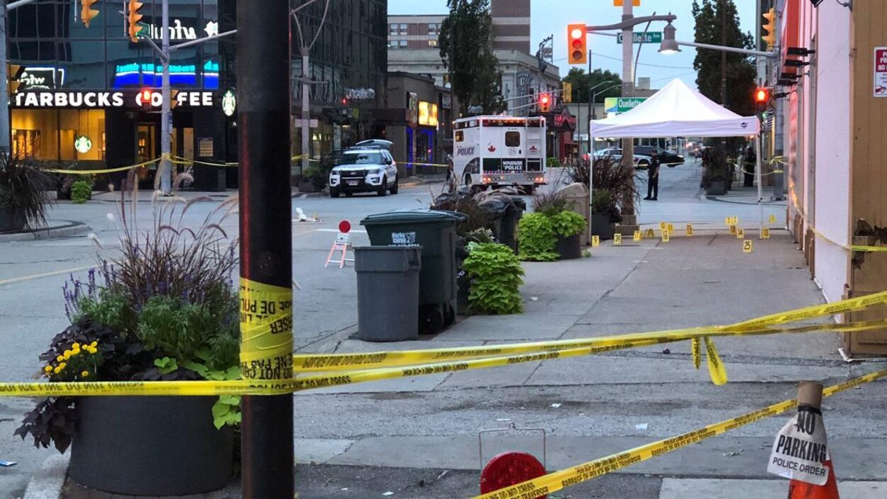 Scène de crime dans une rue. Des bandes jaunes sont au premier plan. Derrière, il y a plusieurs véhicules de police. Scène de crime dans une rue. Des bandes jaunes sont au premier plan. Derrière, il y a plusieurs véhicules de police.