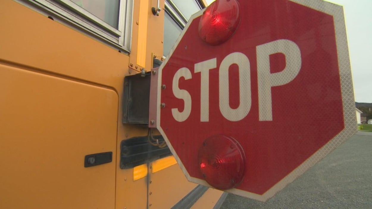 Gros plan sur un panneau-stop déployé d'un bus scolaire.