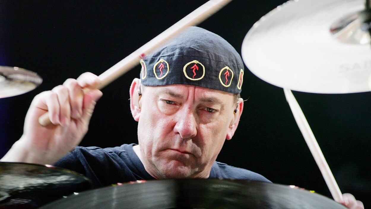 Gros plan du visage de Neil Peart pendant qu'il joue de la batterie.