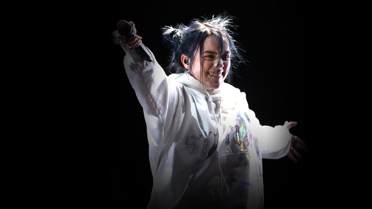 Billie Eilish pointe son micro en direction du public.
