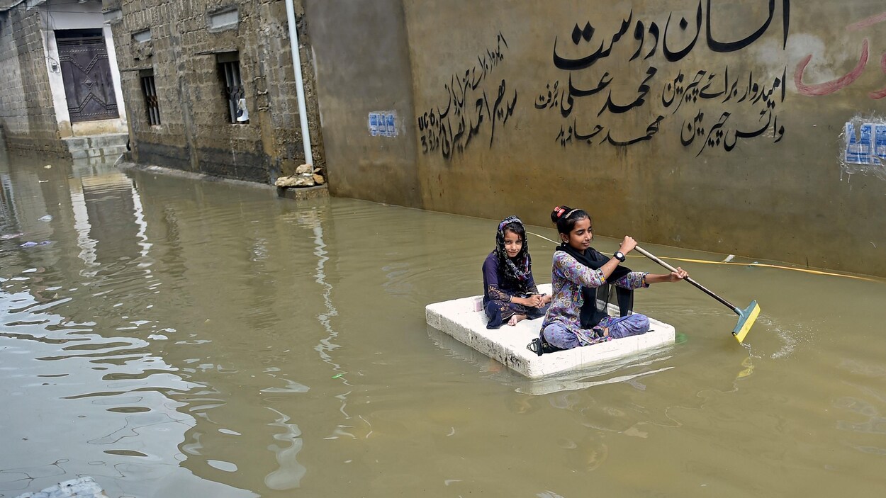 Deux jeunes filles naviguent sur un matelas dans une rue.
