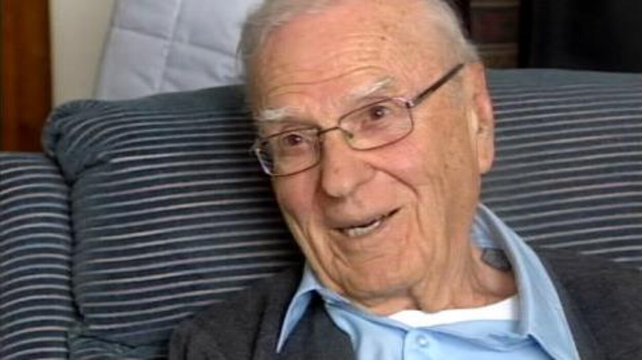 Un homme âgé fait un sourire à la caméra.
