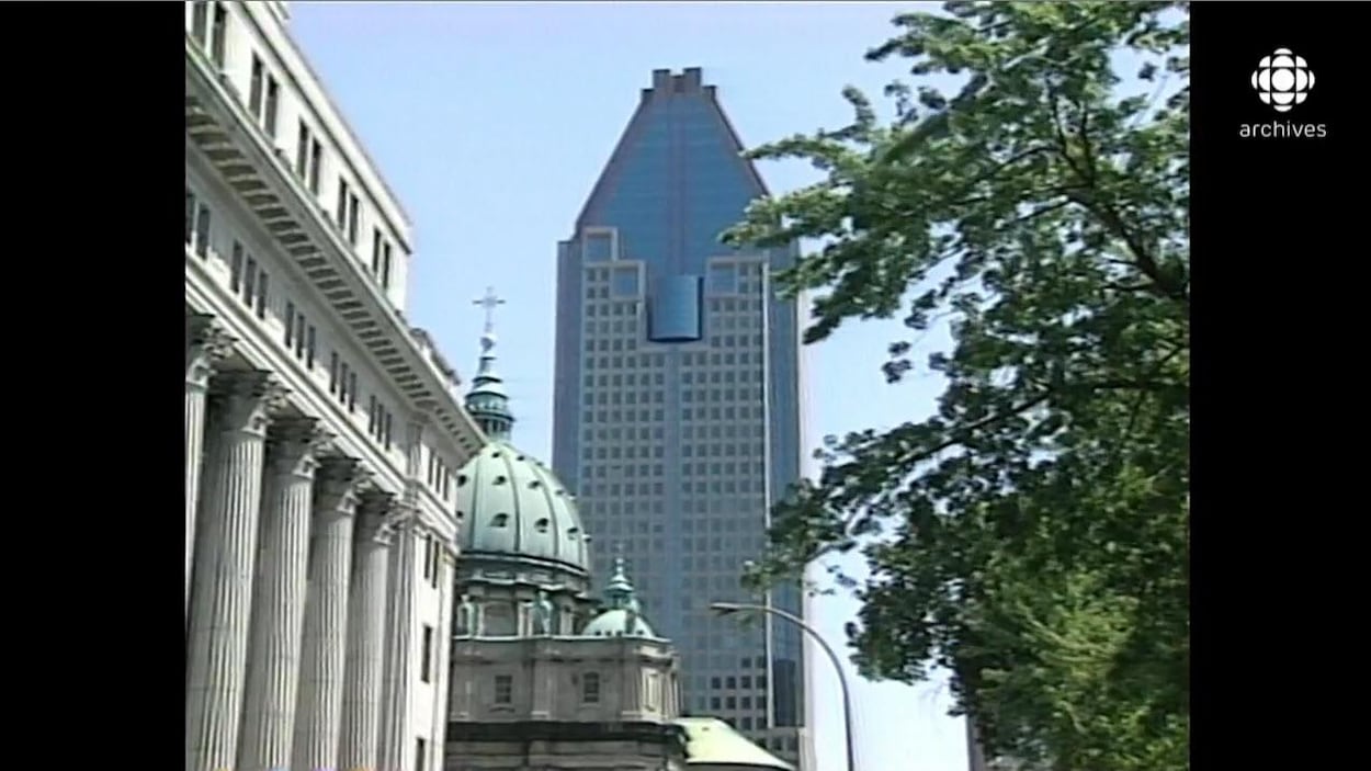 Vue sur la tour du 1000 de la Gauchetière, entre les arbres et les autres bâtiments du square Dorchester, au centre-ville de Montréal