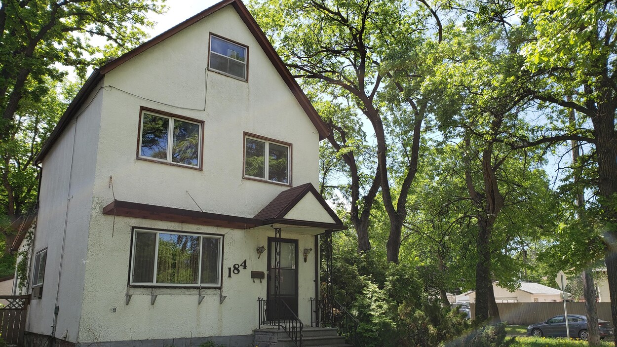 Une maison à deux étages entourée d'arbres.