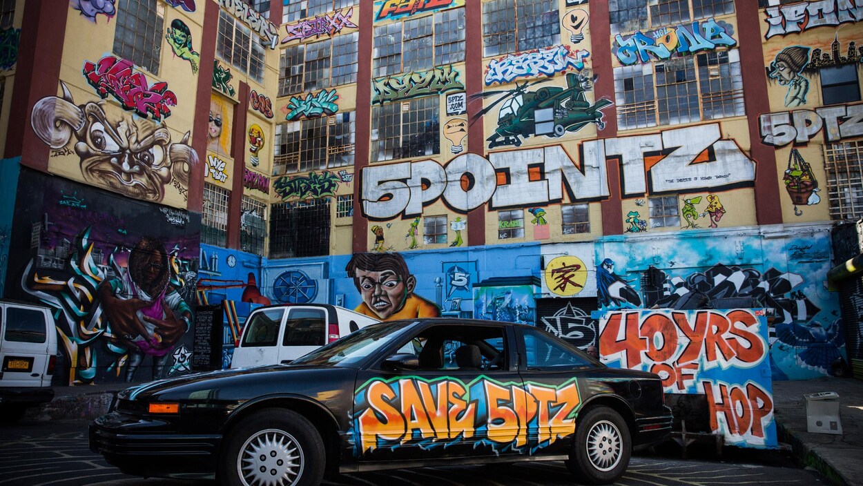 L'édifice 5Pointz en octobre 2013, recouvert de graffitis. On y voit notamment un hélicoptère, une ampoule ou encore un homme regardant vers le bas. L'édifice 5Pointz en octobre 2013, recouvert de graffitis. On y voit notamment un hélicoptère, une ampoule ou encore un homme regardant vers le bas.