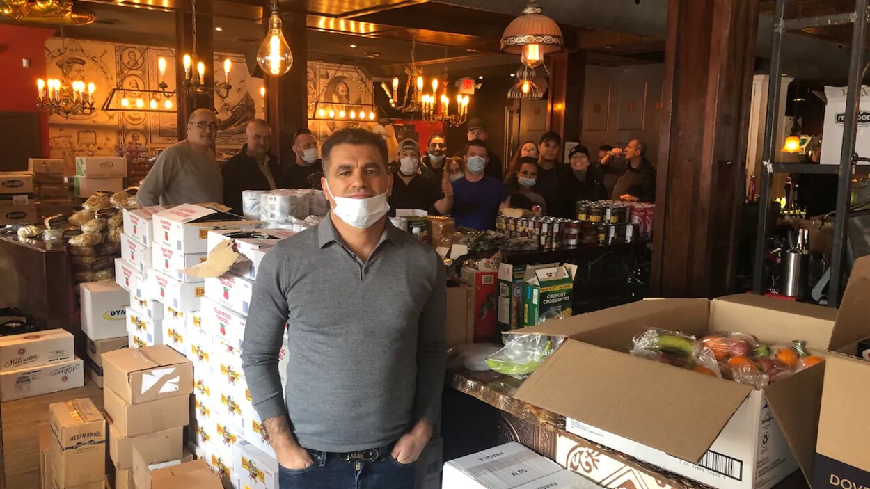 Abbis Mahmoud devant des boîtes de denrées et une équipe de bénévoles.