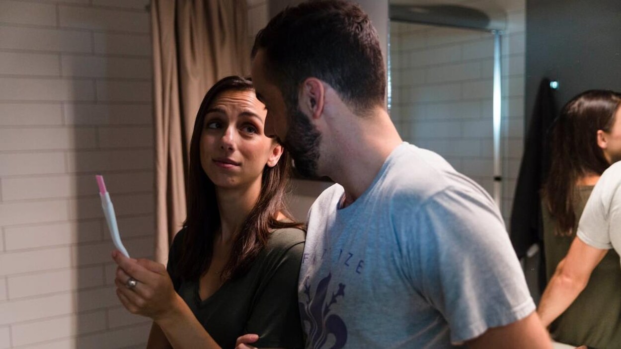 Une femme montre un test de grossesse à un homme.