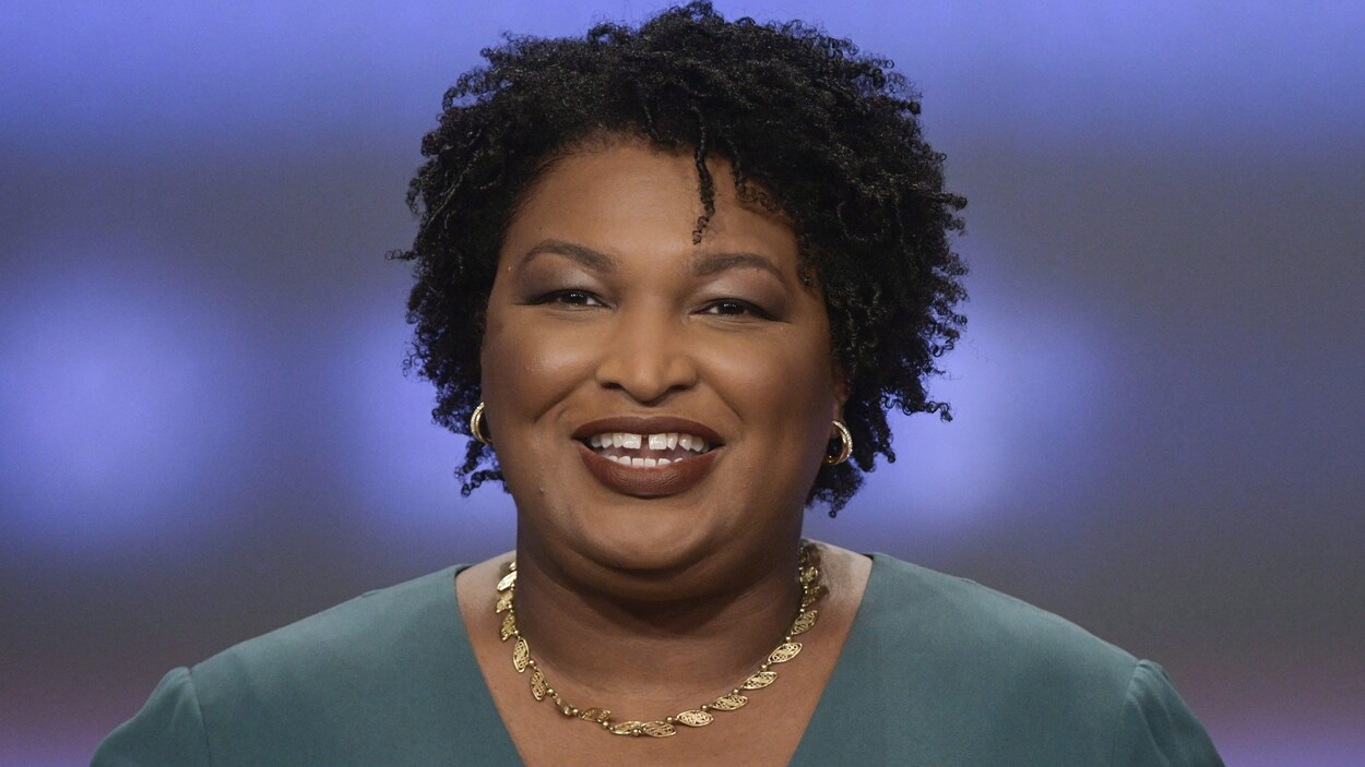 Stacey Abrams, vêtue de vert, sourit à la caméra.