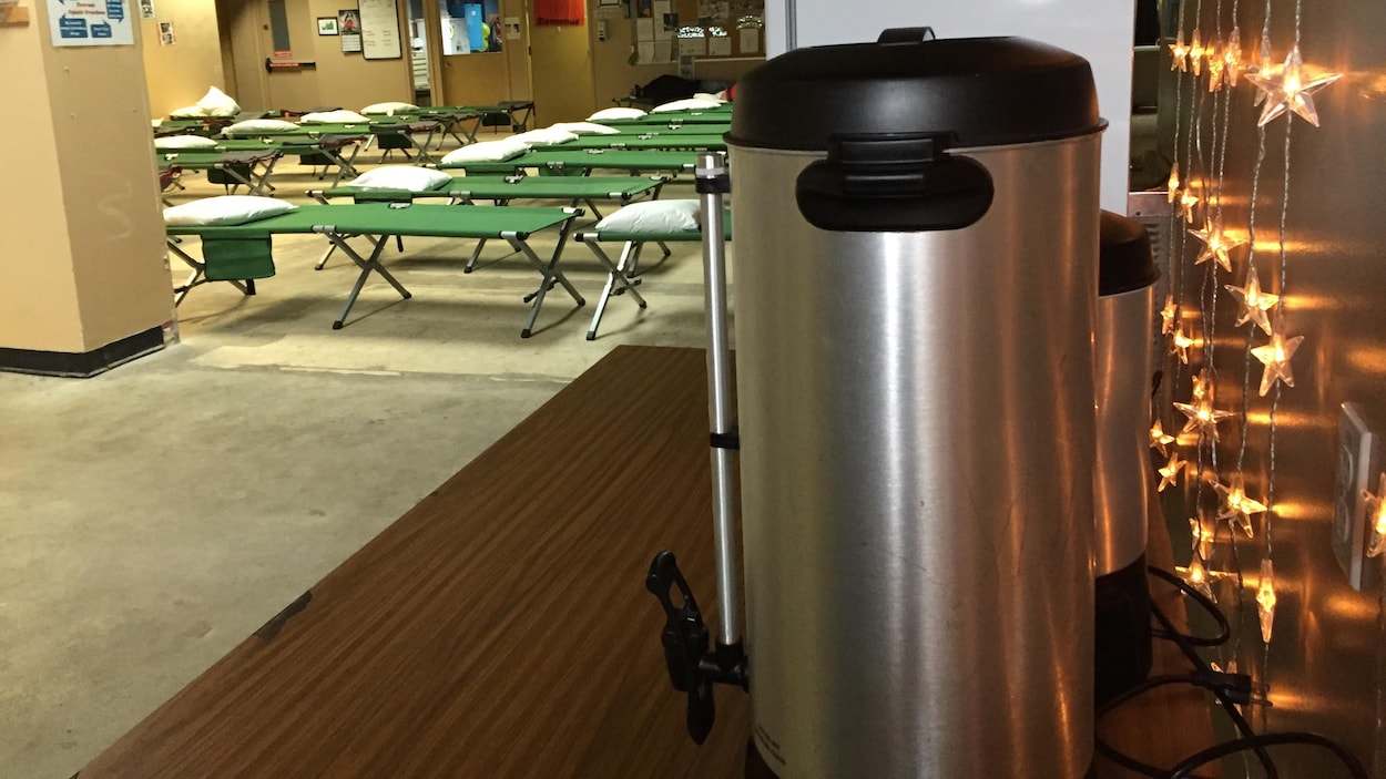 Une cafetière et des lits de camp dans un refuge pour sans-abri