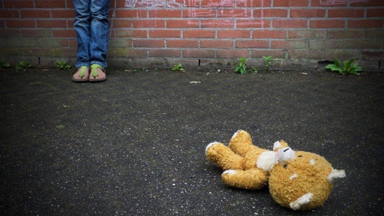 Un toutou repose au sol devant un enfant que l'on voit partiellement.