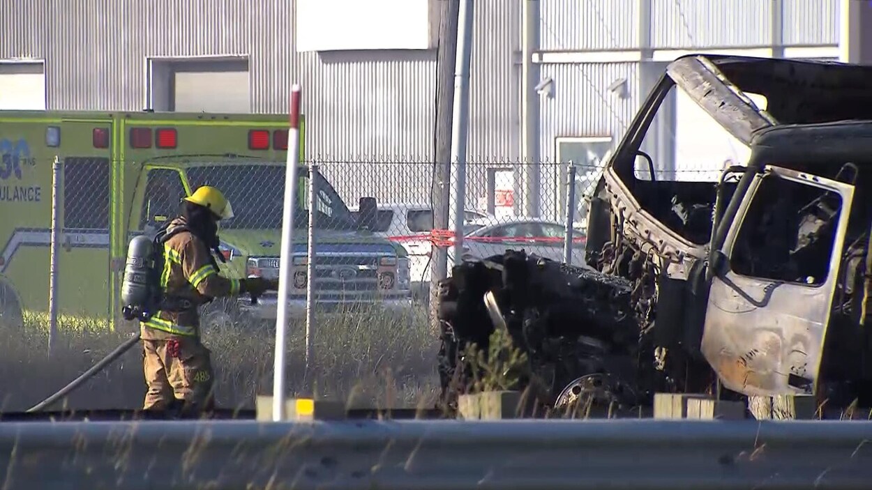 Un pompier finit d'asperger la carcasse d'un camion calciné.
