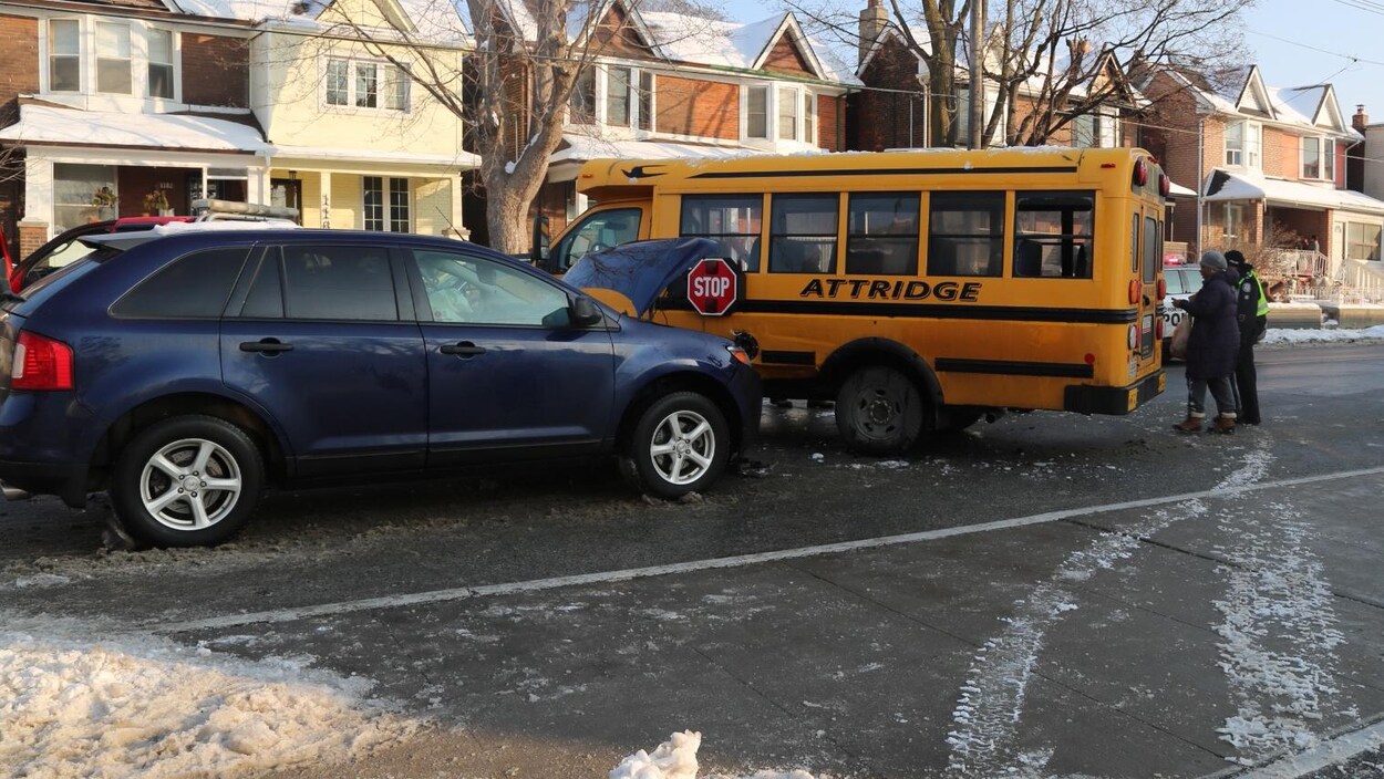 Photo montrant un VUS bleu, le capot ouvert, qui a percuté un petit autobus scolaire jaune en travers de la rue. Photo montrant un VUS bleu, le capot ouvert, qui a percuté un petit autobus scolaire jaune en travers de la rue.
