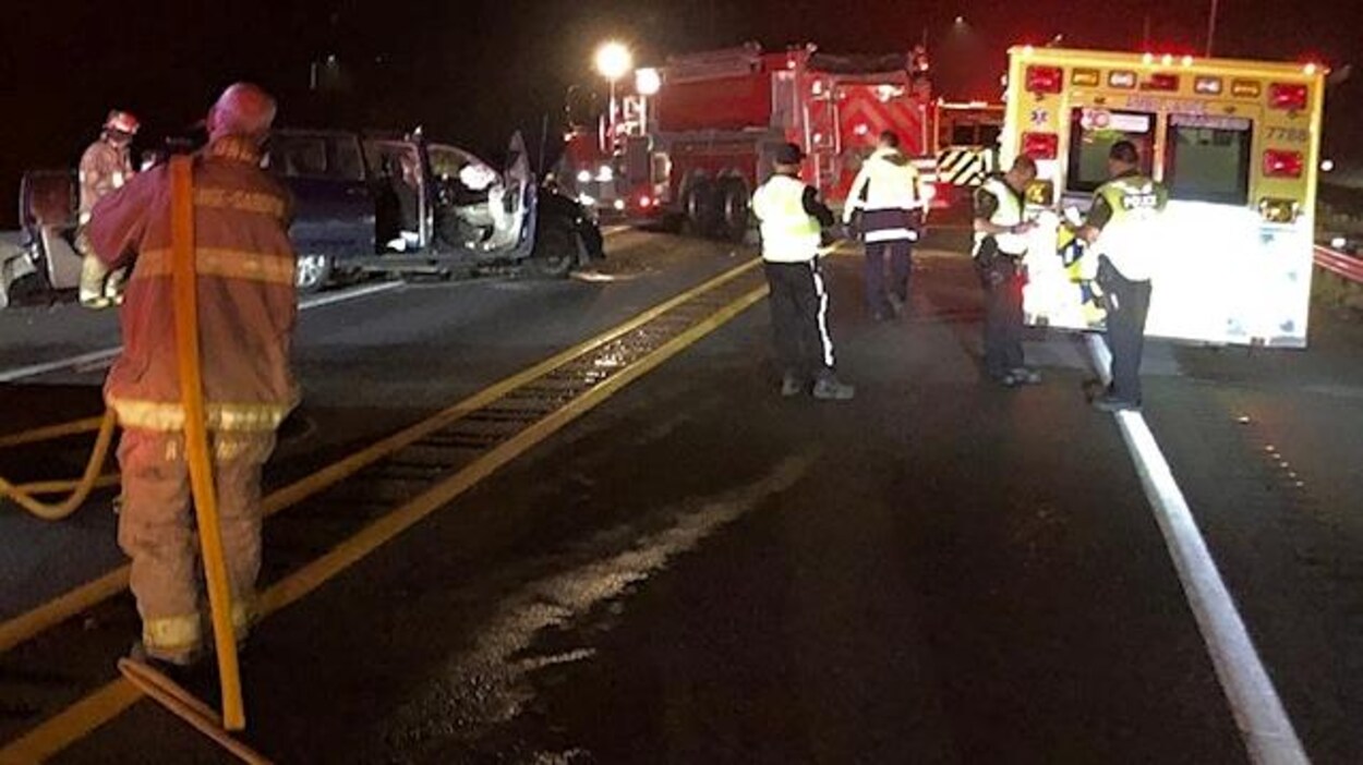 Des pompiers, ambulanciers et policiers entourent un des véhicules accidentés.
