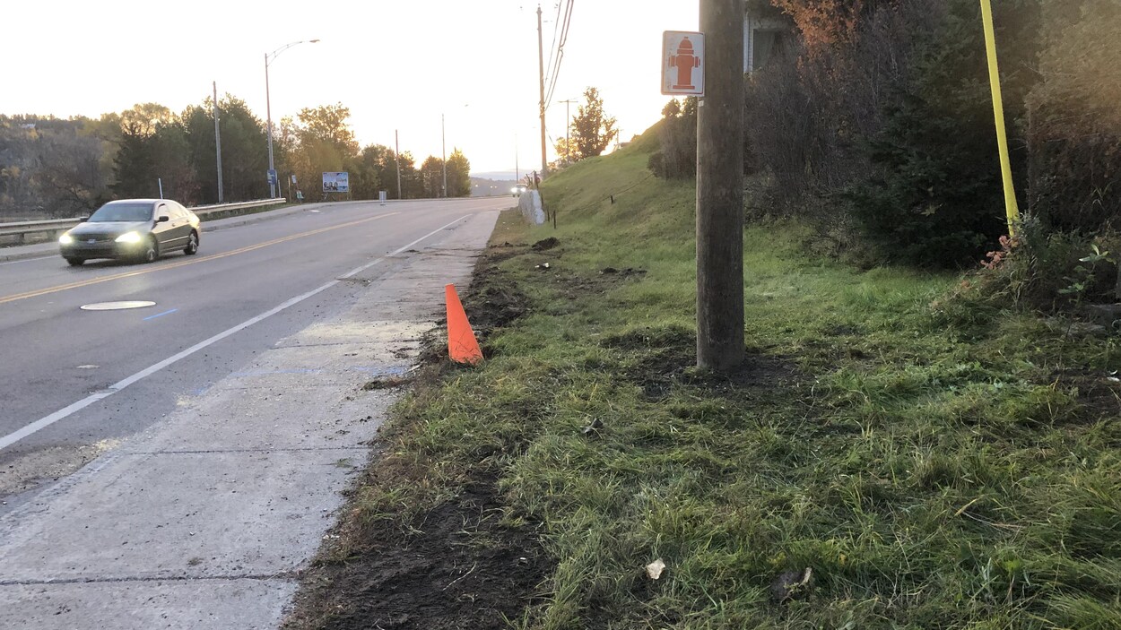 Un cône orange et un poteau d'électricité en bordure du boulevard Saguenay.