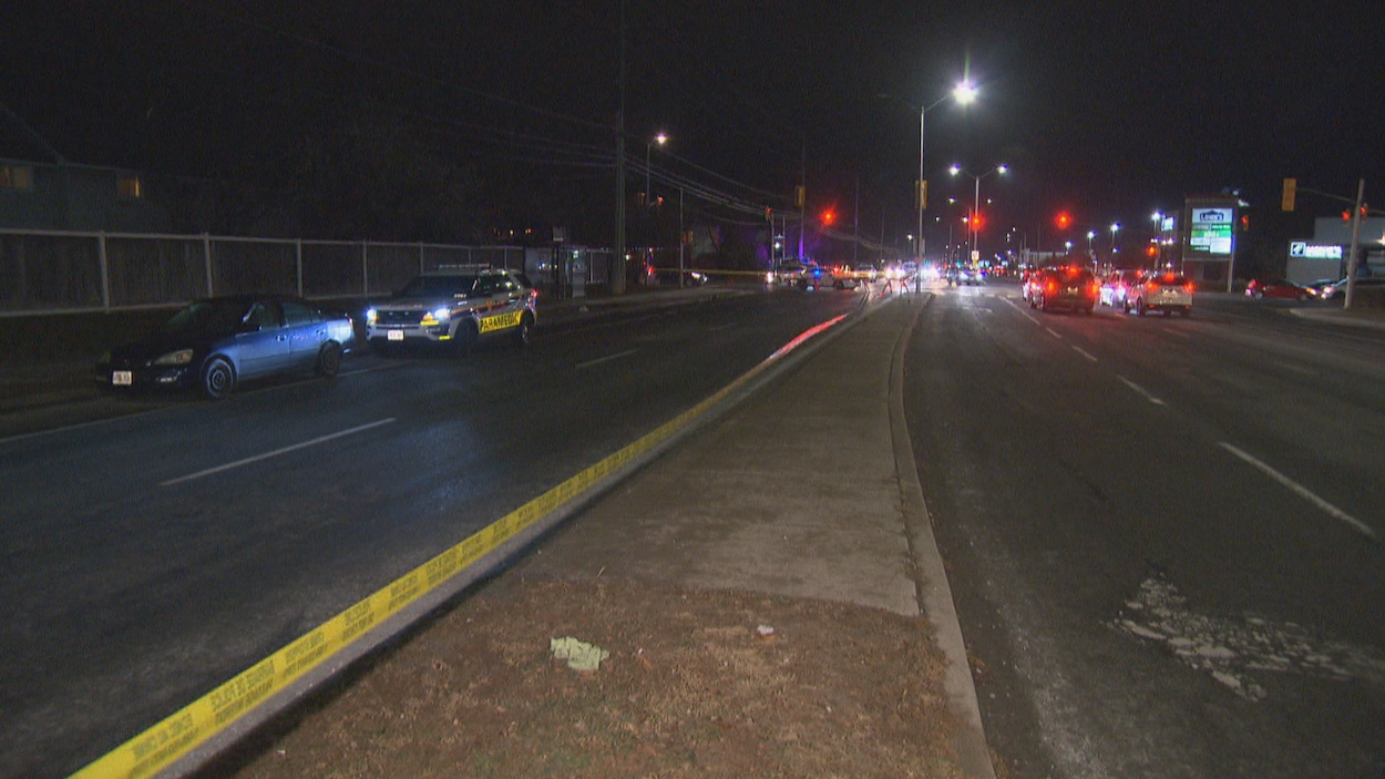 Un véhicule de la police d'Ottawa garé derrière une autre voiture sur on tronçon de route entouré d'un cordon de sécurité.