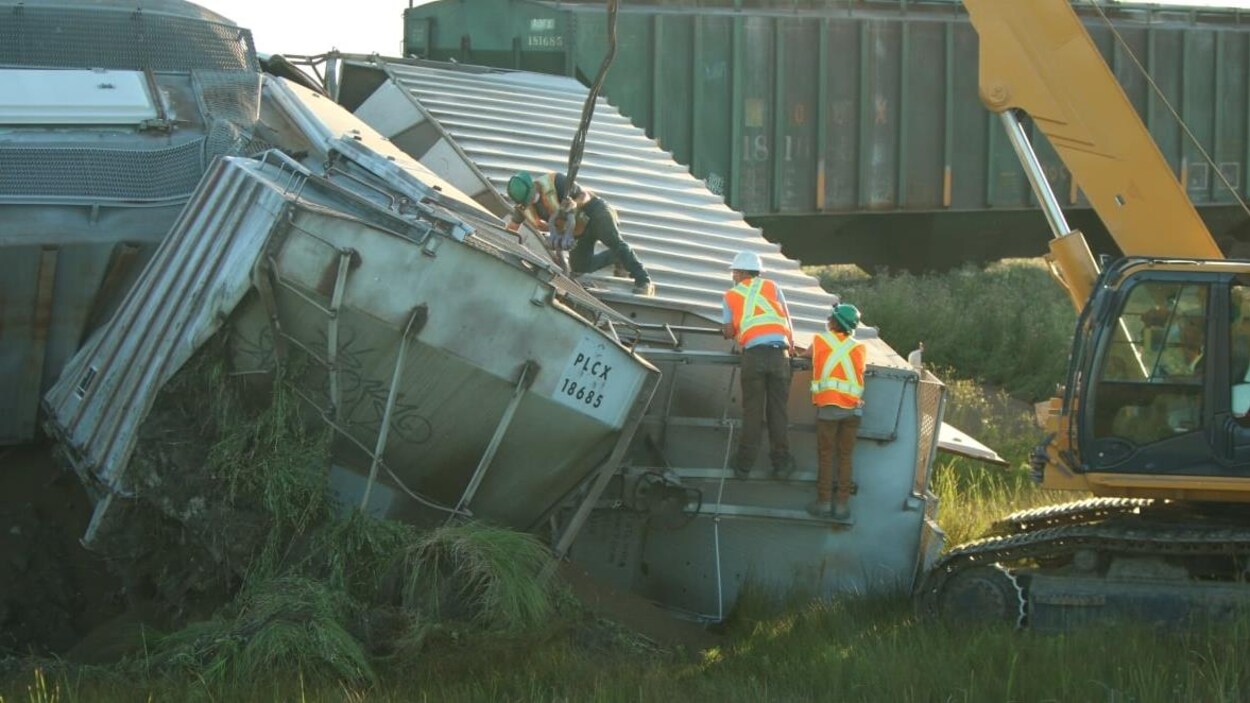 Des employés du Canadien National sur et près des wagons qui ont déraillé.