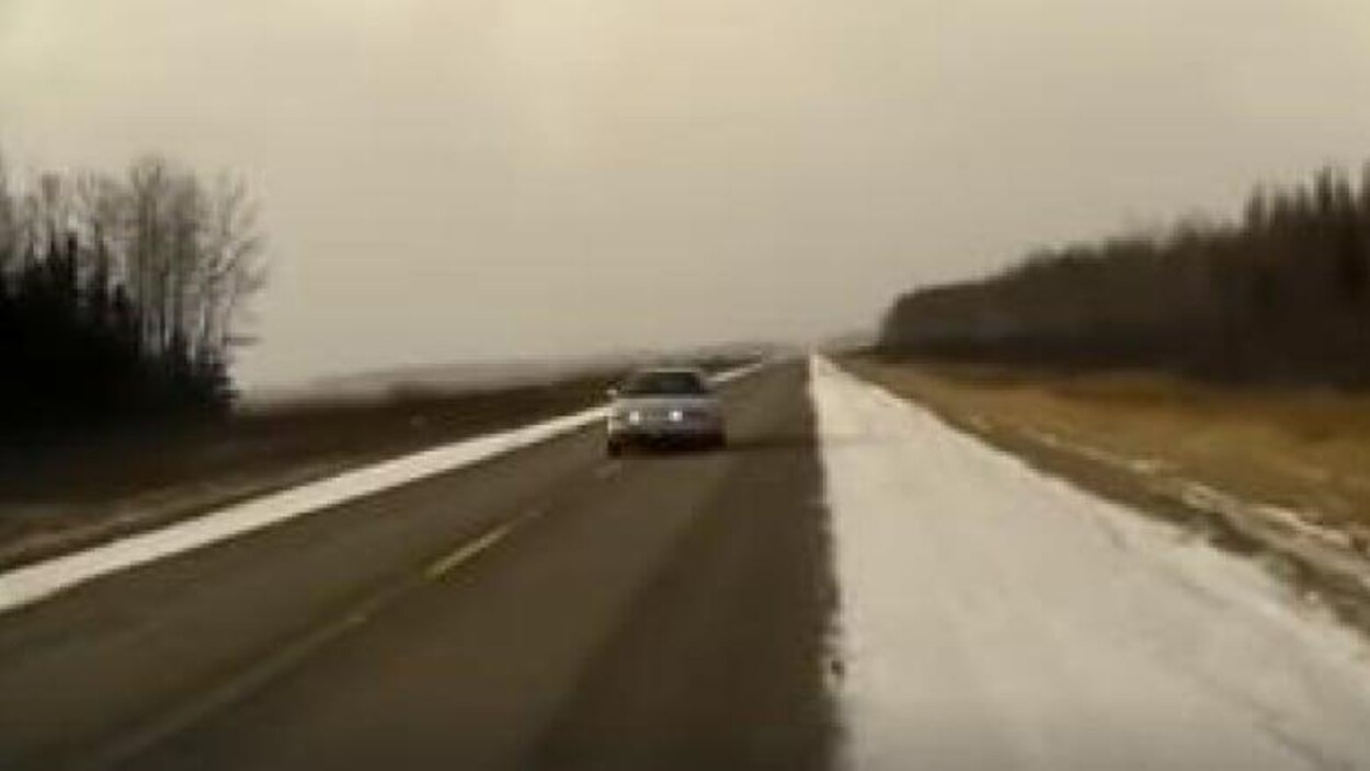 Une voiture roule sur une route.