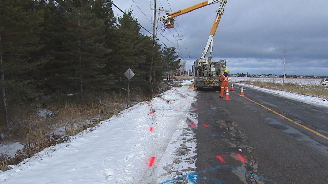 Des lignes rouges sur la chaussée se rendent jusqu'à un poteau de téléphone, près d'un camion d'Hydro-Québec.