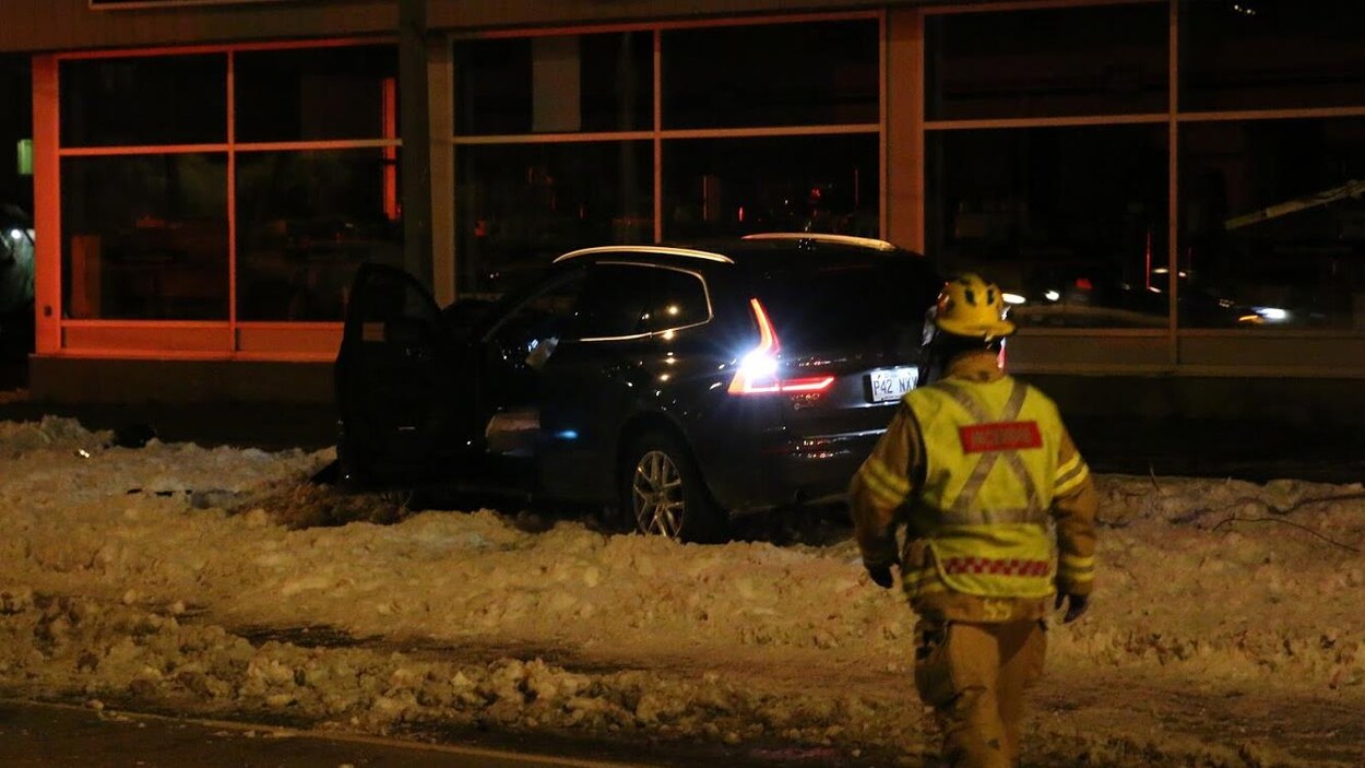 Un pompier s'approche de la voiture immobilisée, la porte ouverte