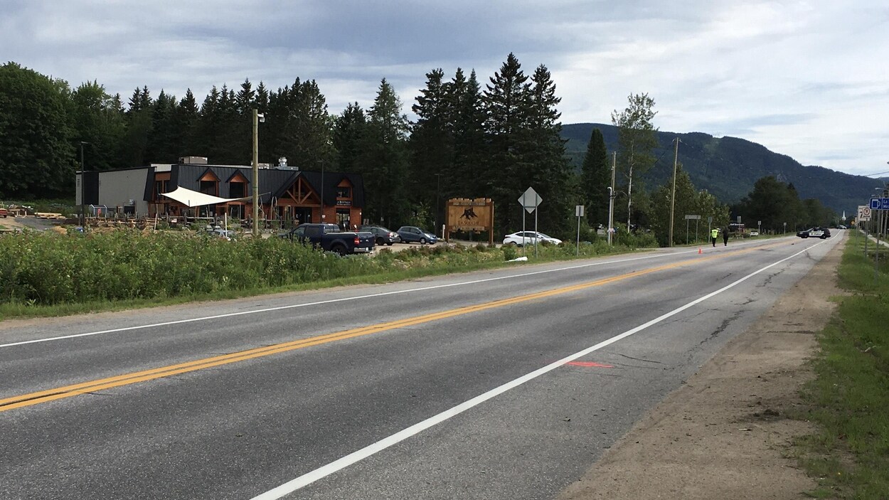 Une autoroute devant une montagne. Des policiers circulent sur la chaussée, devant le bar La Souche.