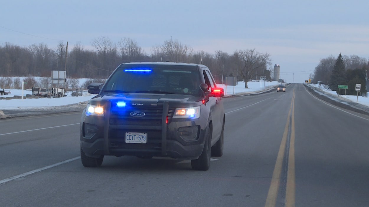 Une voiture de police bloque une route.