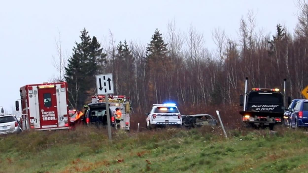Scène d'accident dans une route à double sens avec une voiture de police et une ambulance.