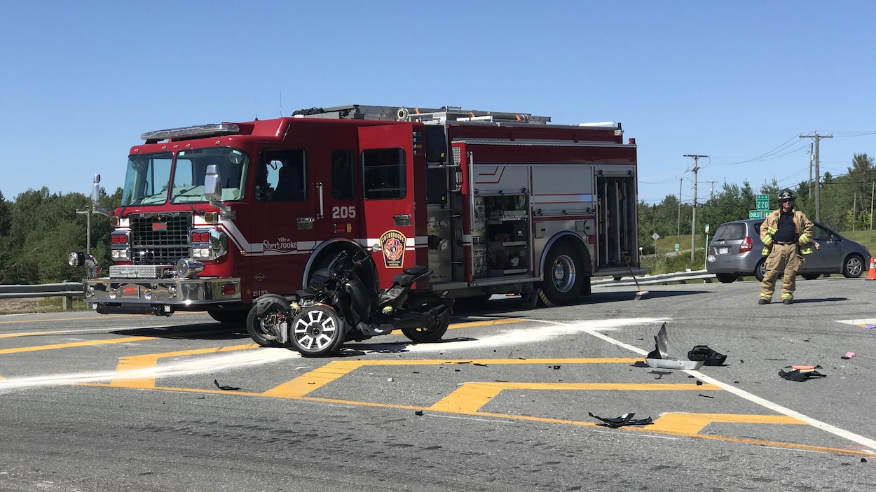 Une motocyclette endommagée devant un camion de pompier.