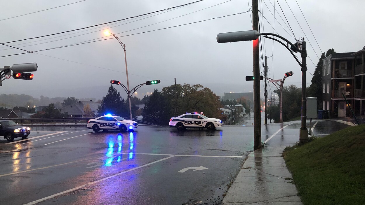 Deux véhicules de police sont arrêtés à une intersection.