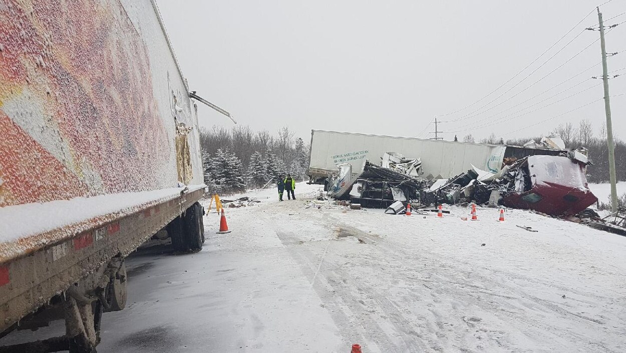 Deux camions sont immobilisés sur une route enneigée. L'une d'entre eux est éventré. Deux camions sont immobilisés sur une route enneigée. L'une d'entre eux est éventré.