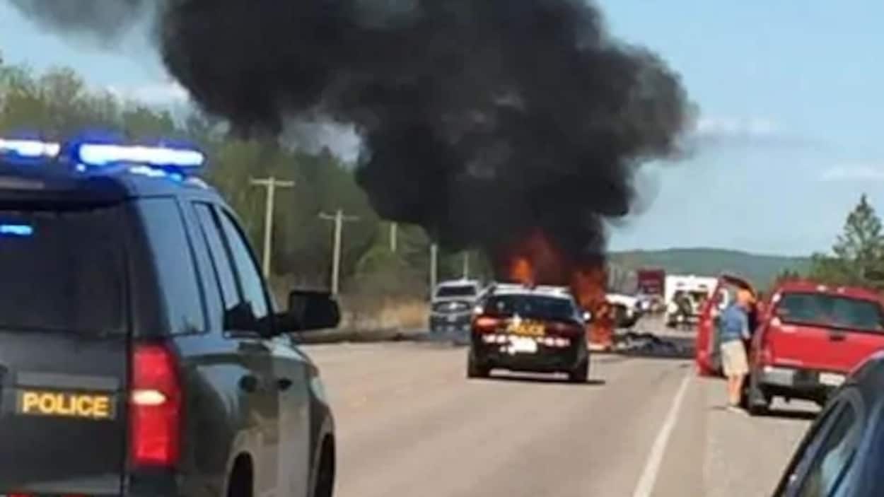 Des voitures de polices près d'un véhicule en feu.