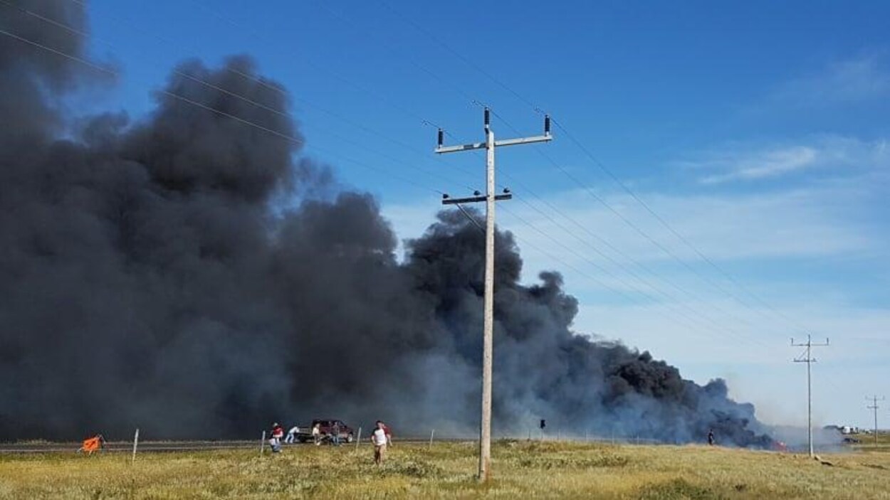Des personnes fuient une route envahie par une épaisse fumée.