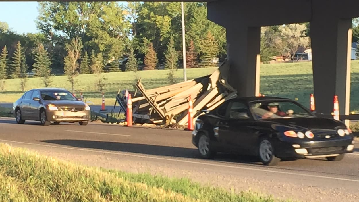 Des voitures passent à côté des débris placés au bord de la route.