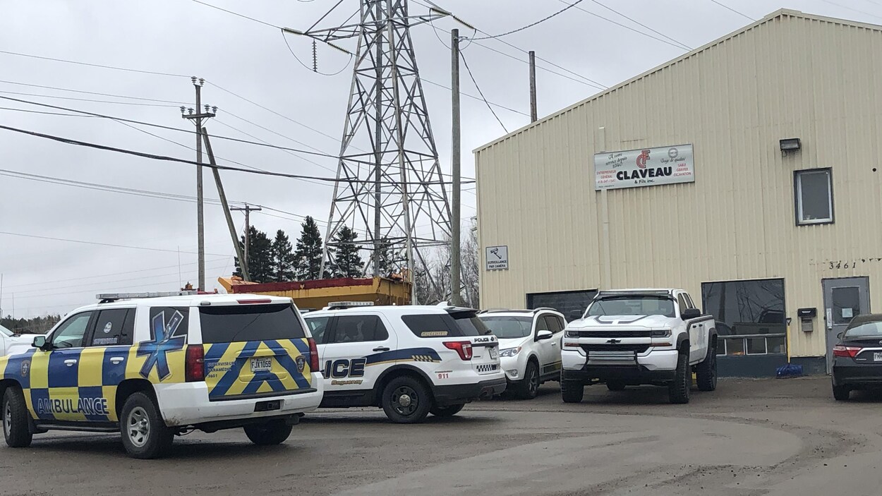 Une voiture de police et une voiture-ambulance dans le stationnement de l'entreprise.