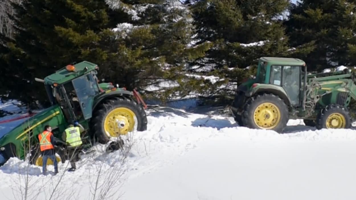 L'homme tentait de déplacer un tracteur qui était enseveli dans la neige. L'homme tentait de déplacer un tracteur qui était enseveli dans la neige.