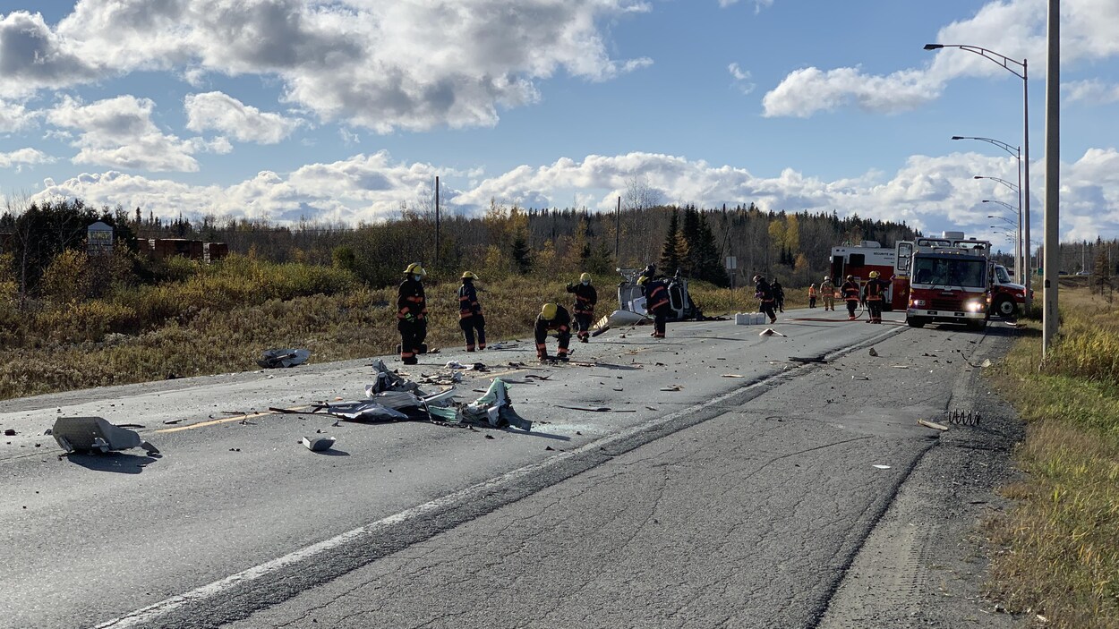 Des pompiers ramassent des débris sur la route sur le site d'un accident.