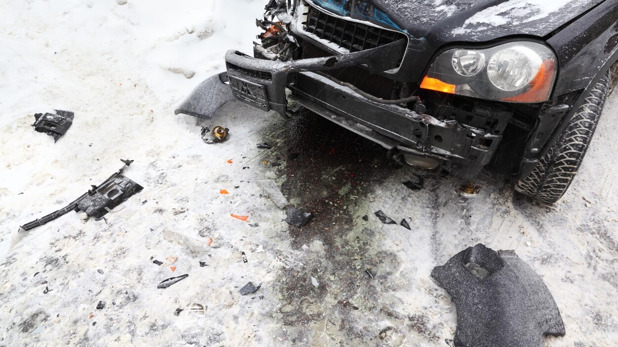 Une voiture noire accidentée sur une route enneigée Une voiture noire accidentée sur une route enneigée