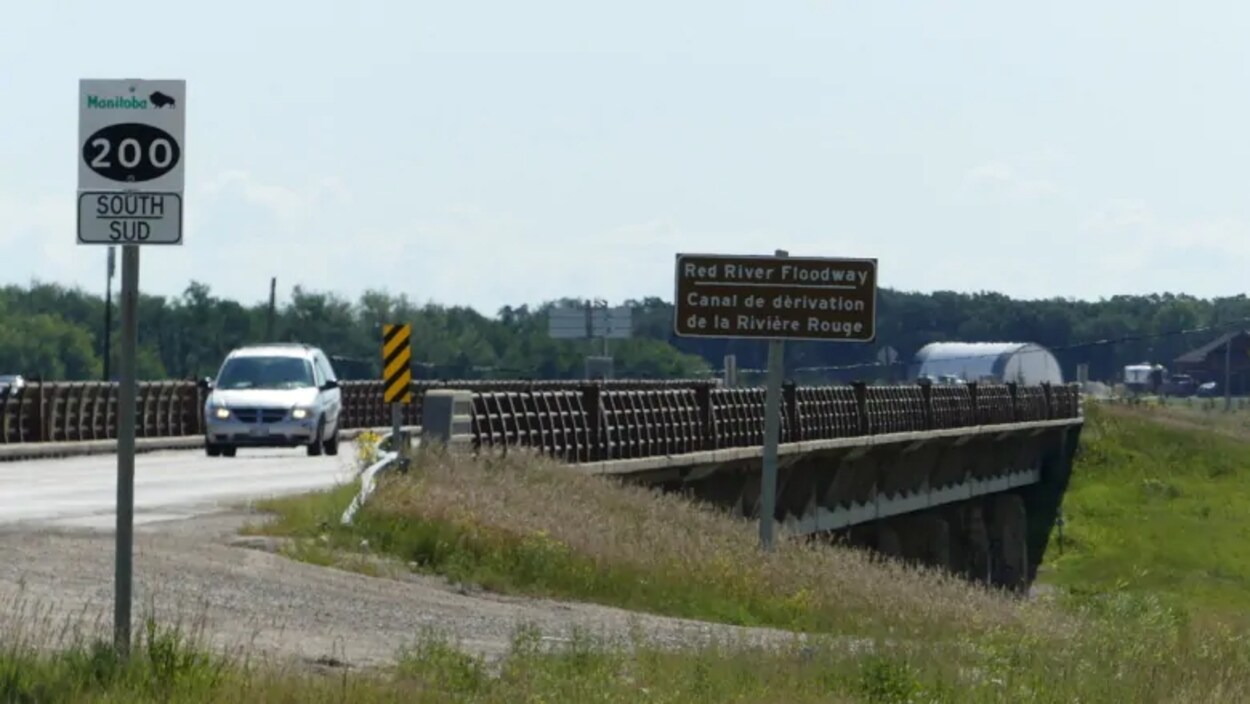 Deux véhicules traversent un pont sur un canal de dérivation.