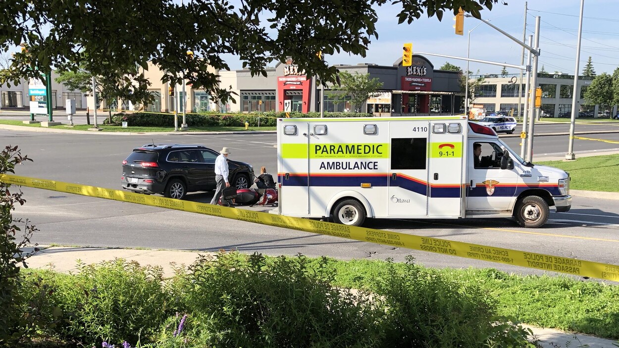 Un périmètre de sécurité à l'intérieur duquel se trouvent une ambulance, un véhicule utilitaire sport et une motocyclette.