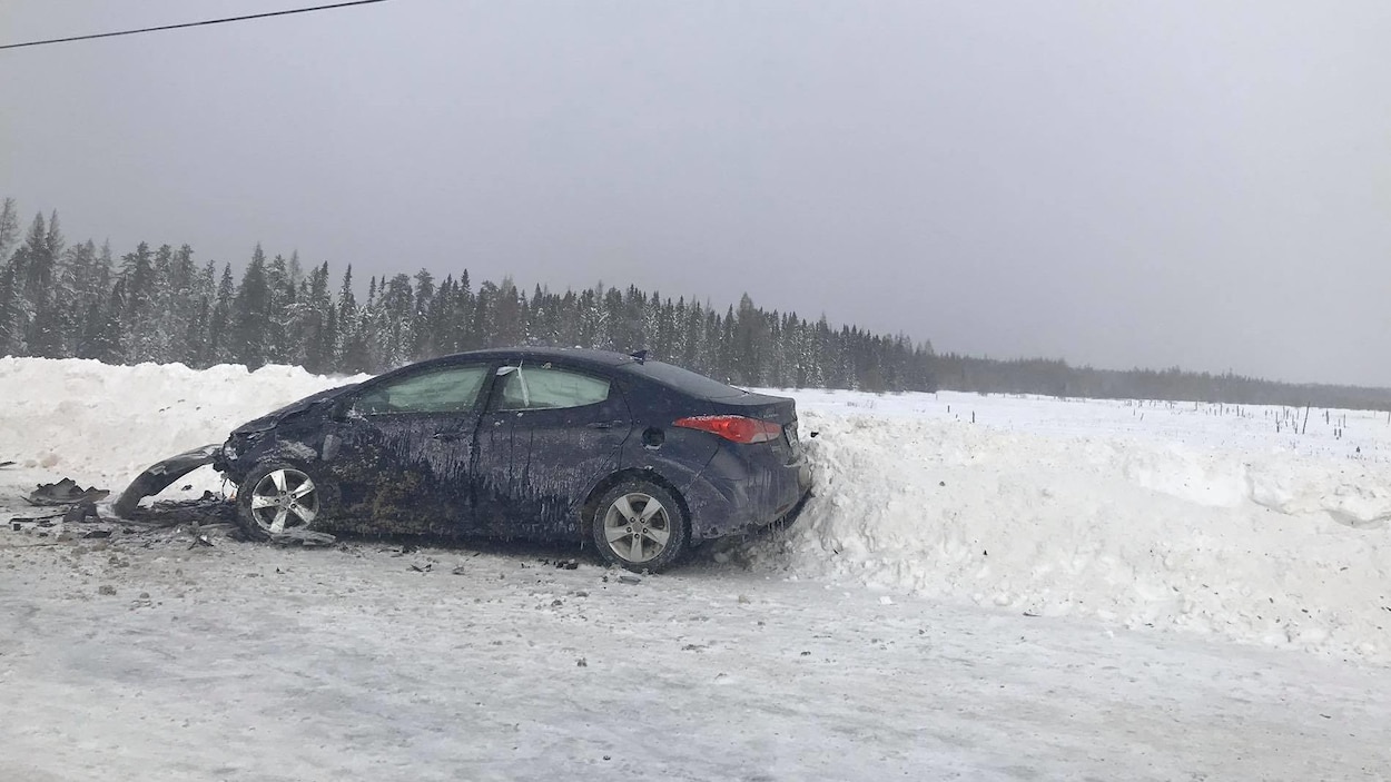 Une voiture avec le capot démoli est sur le bord de la route.