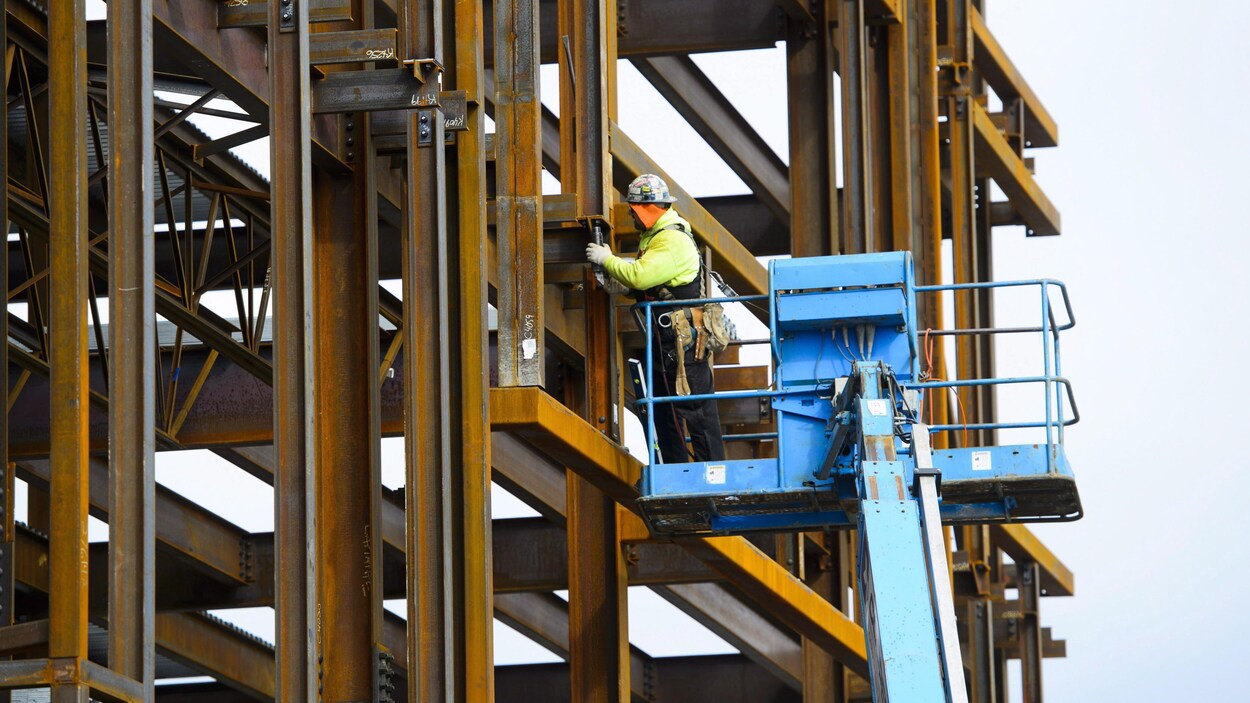 Un travailleur monte une structure en acier.