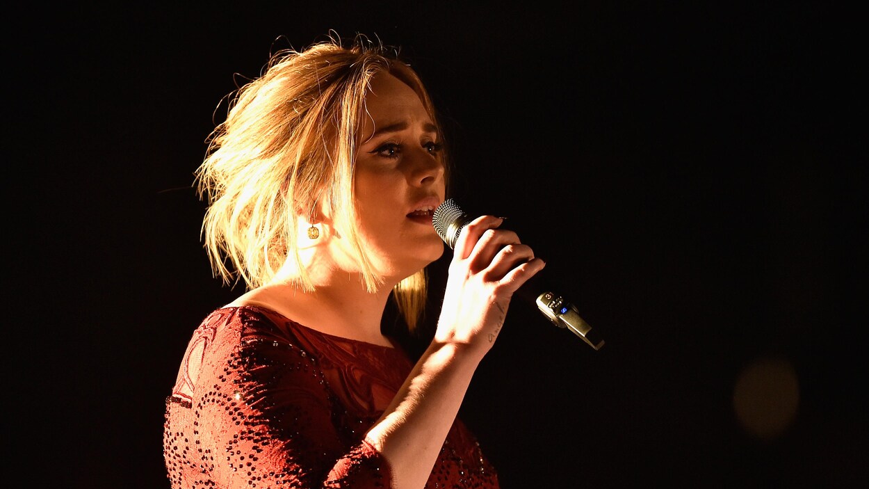 La chanteuse Adele chante sur scène vêtue d'une robe rouge lors de la cérémonie de remise des prix Grammy en 2016.